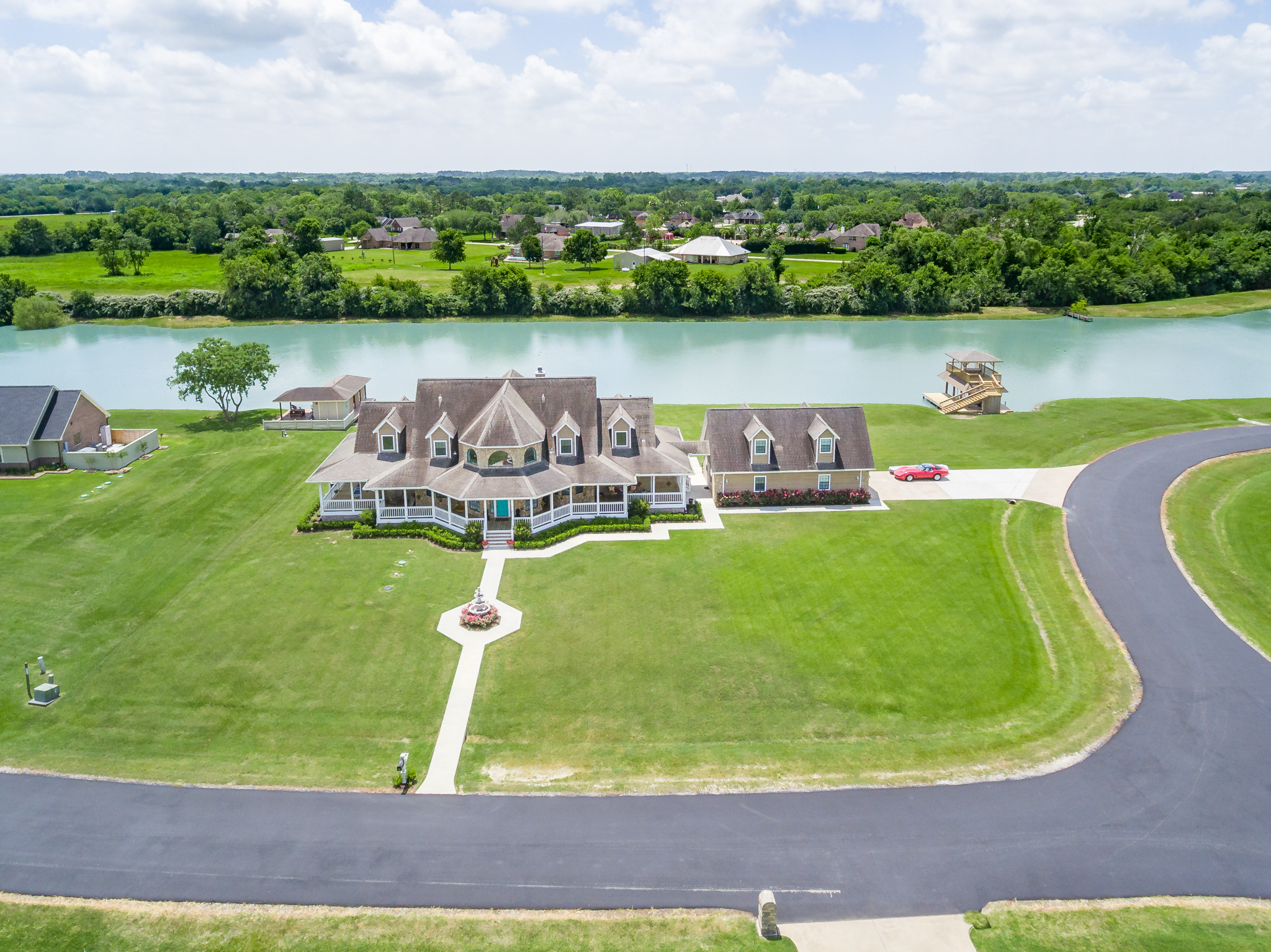 Aerial view of a waterfront home with a long circular drive