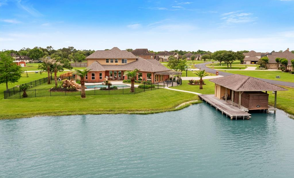 Aerial view of a Lago Santa Fe waterfront home with pool, palms and boathouse on the private lake