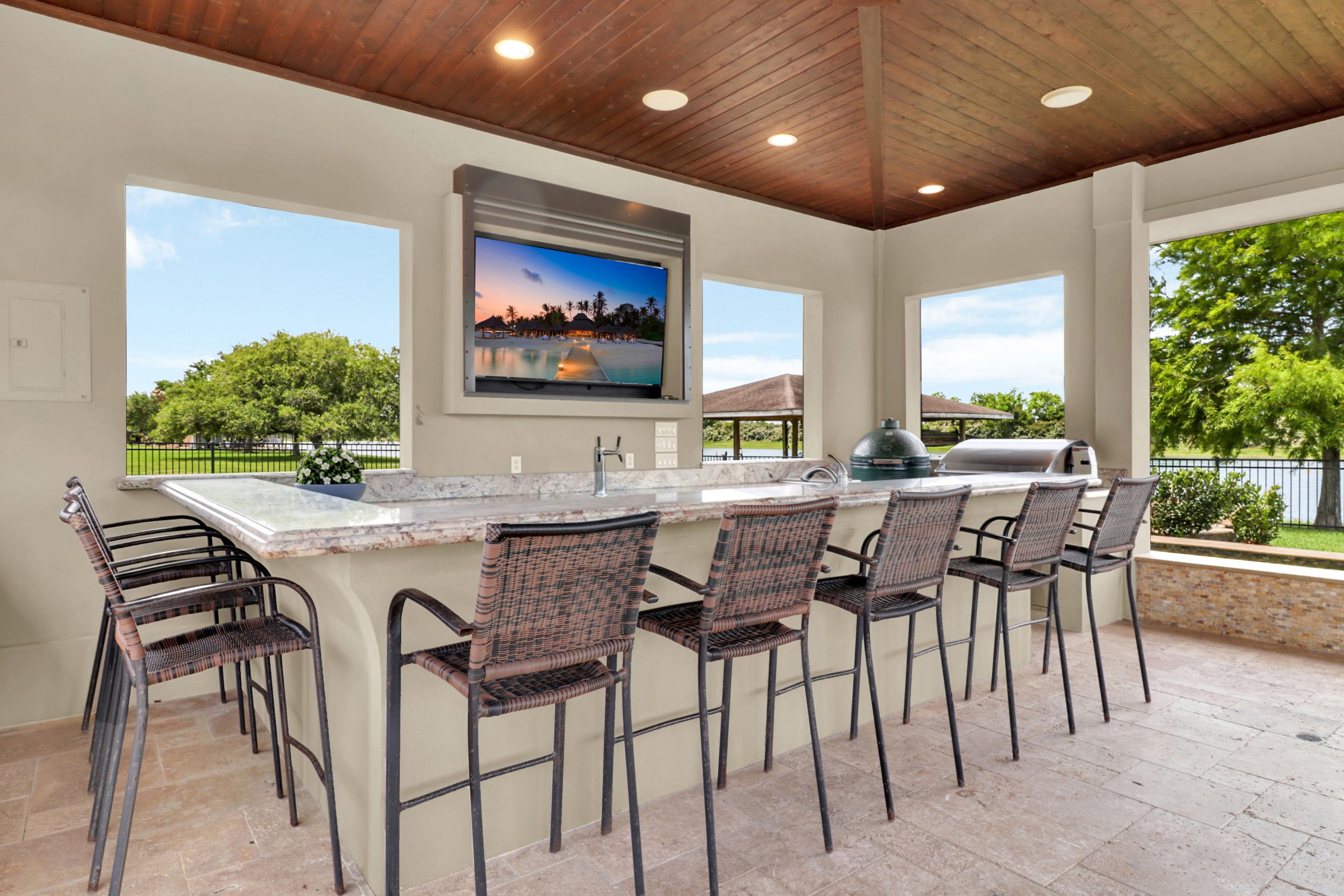 Covered outdoor kitchen and bar with a mounted TV