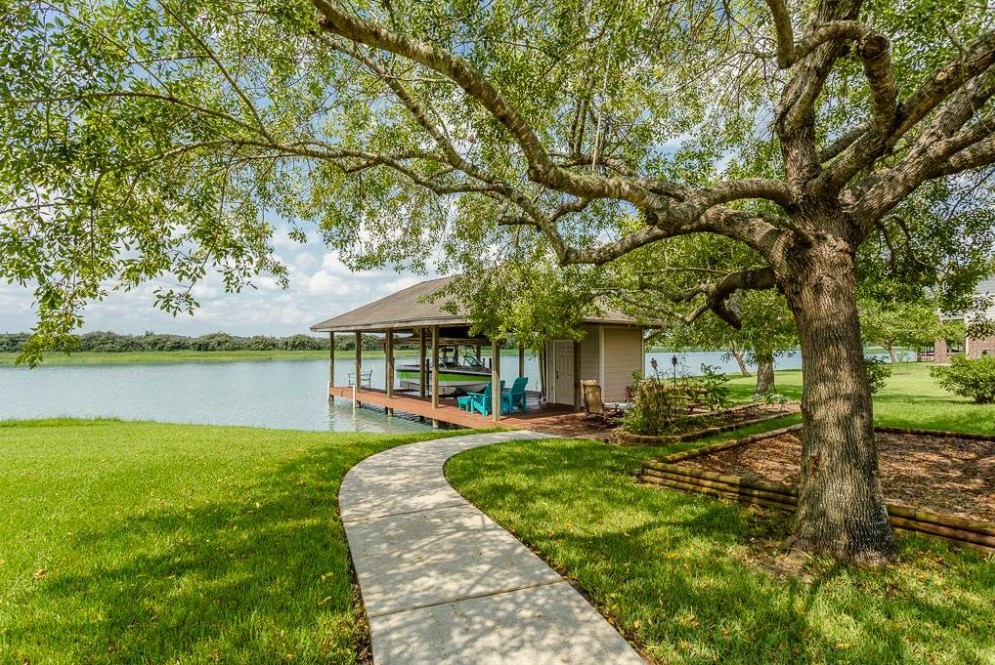 Lakefront lawn with boathouse under a large oak tree