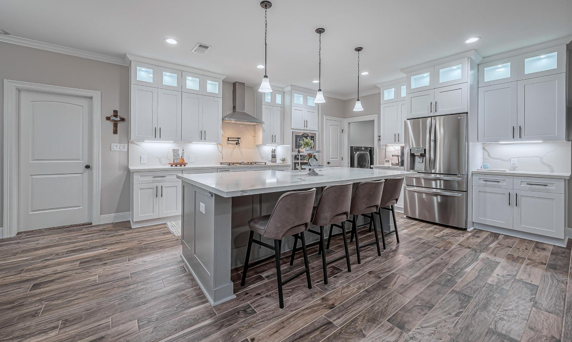 Kitchen with white cabinetry, large island and stainless appliances