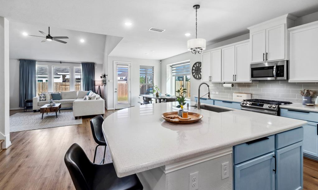 Bright open kitchen with white cabinets, island and living area